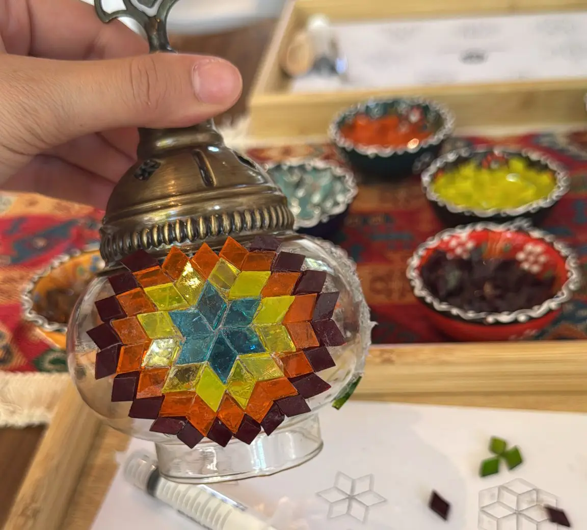 Nahaufnahme einer Mosaiklampe, die mit bunten Glassteinen beklebt wird