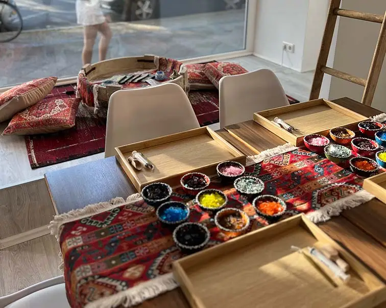 Mosaiktisch mit bunten Glasperlen, Werkzeug und orientalischem Hintergrund im Orient Art Studio Berlin