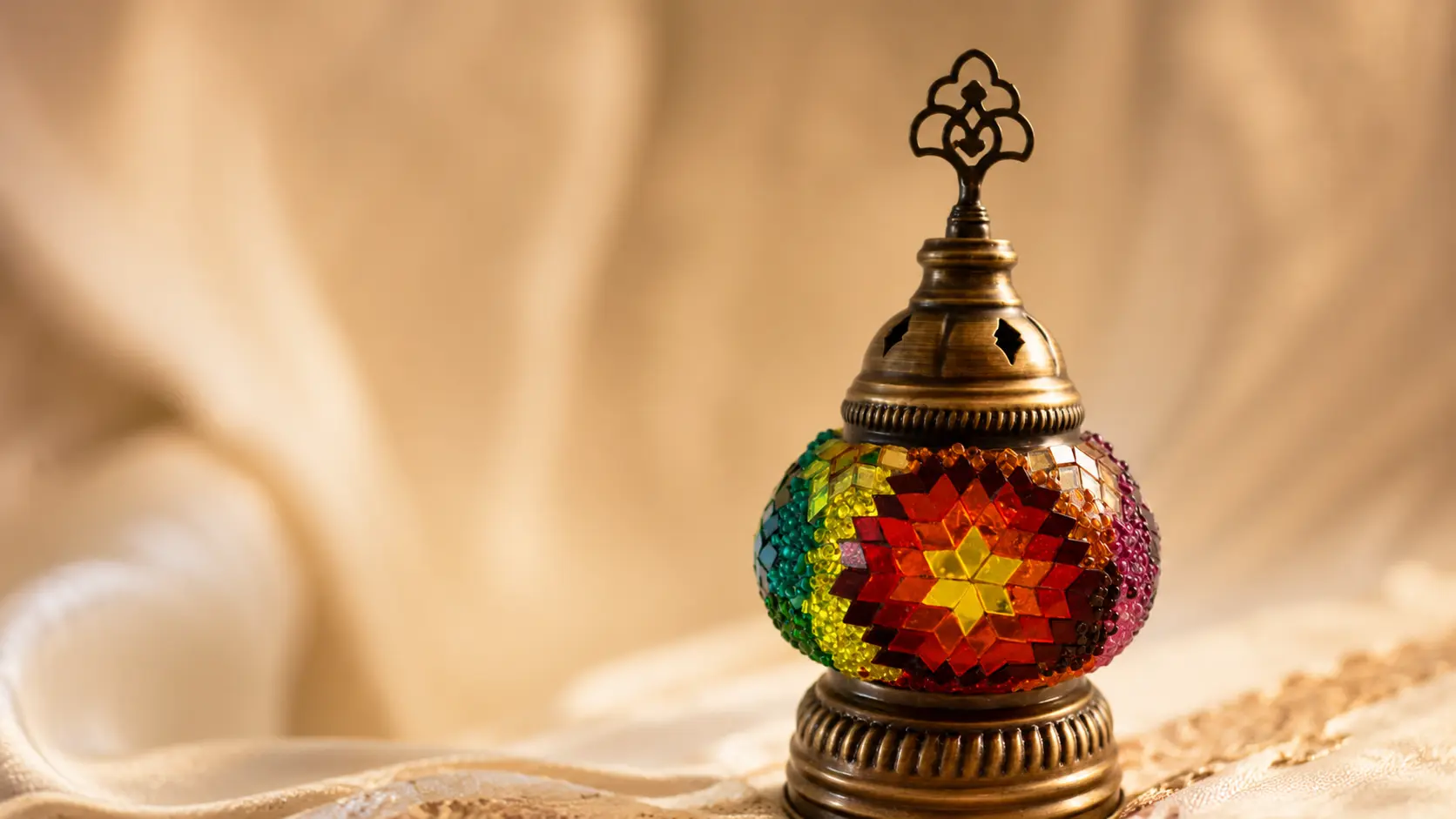 Makroaufnahme einer handgefertigten orientalischen Mosaiklampe mit Glassteinen, Perlen und Messingornamenten im Orient Art Studio Berlin